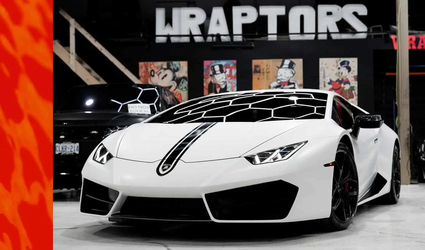 Wraptors Orlando, Vehicle Wraps, PPF & Tint A white sports car with a unique black geometric hood design, expertly protected by PPF, is parked indoors in front of signs and artwork—showcasing the craftsmanship of Wraptors Orlando, a leader in Orlando Florida Car Wraps. Orlando, FL