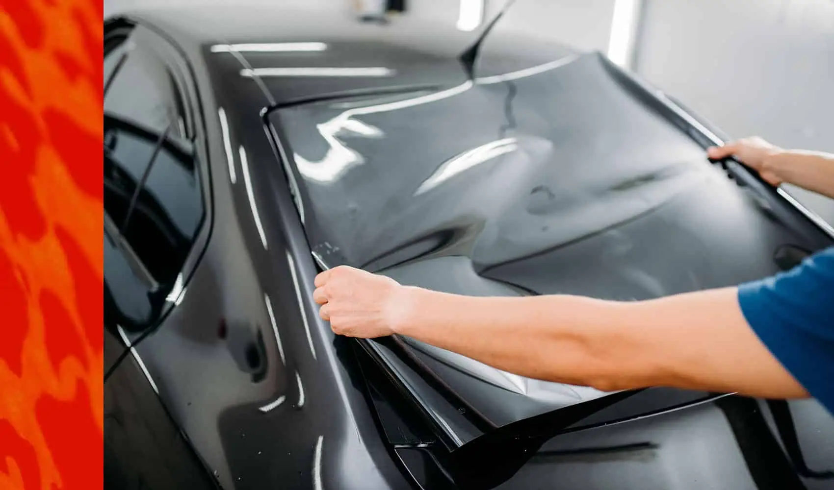Wraptors Orlando, Vehicle Wraps, PPF & Tint A technician from Wraptors Orlando is carefully applying window tint film to the rear windshield of a black car inside a well-lit workspace, showcasing the precision and expertise that Orlando Florida Car Wraps and PPF services are known for. Orlando, FL