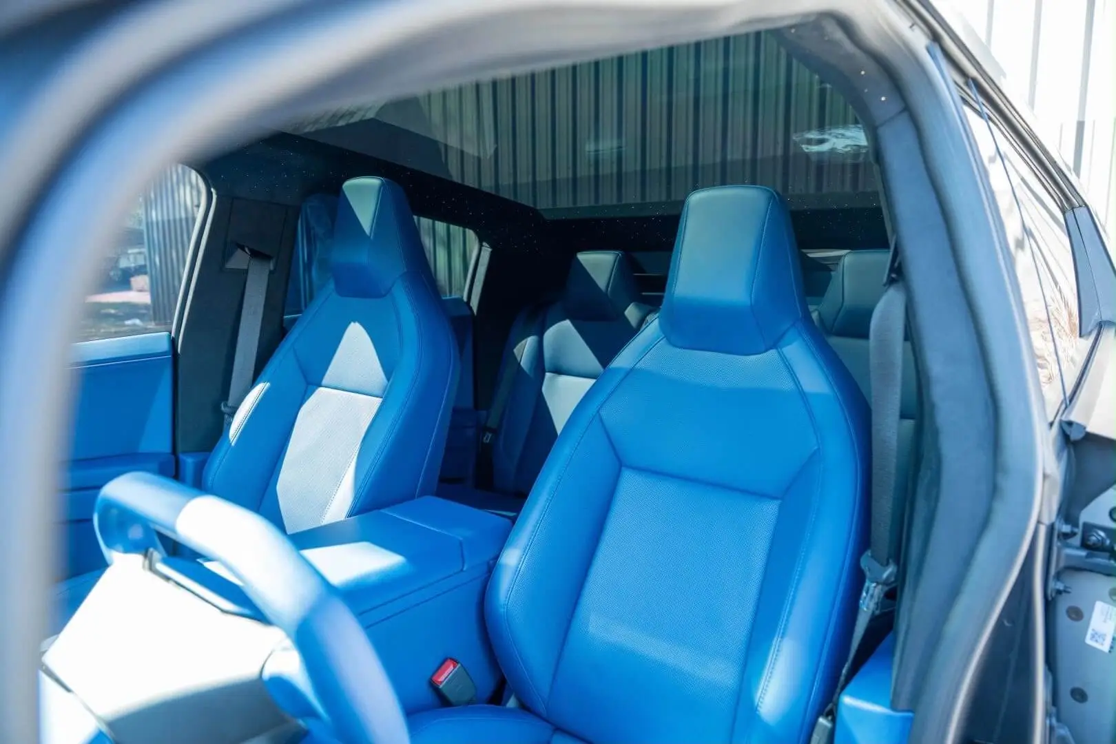 Wraptors Orlando, Vehicle Wraps, PPF & Tint View of a car interior featuring two front blue leather seats, a blue steering yoke, and blue door panels, photographed from outside the open driver's side door—an elegant finish that showcases the precision and style Wraptors Orlando brings to every custom project, making it a standout example of quality Orlando Florida Car Wraps. Orlando, FL